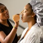 Makeup artist applying cosmetics to a client inside a salon.