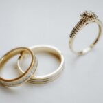 Elegant gold wedding bands and a diamond engagement ring on a plain background, ideal for wedding themes.