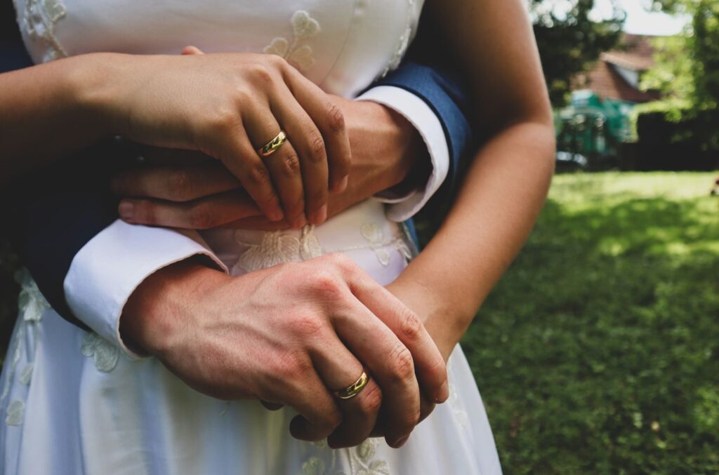 Close-up of couple's hands showing wedding rings, symbolizing love and unity.